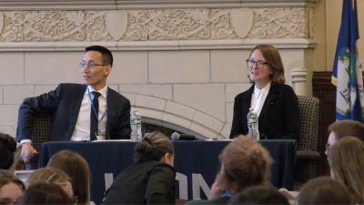 formally dressed man and woman on platform in front of audience