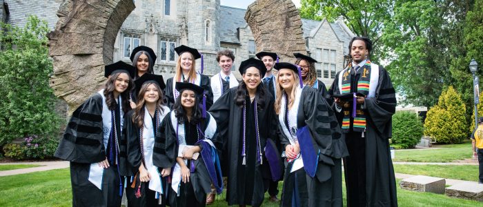 A dozen graduates pose in front of the law library.