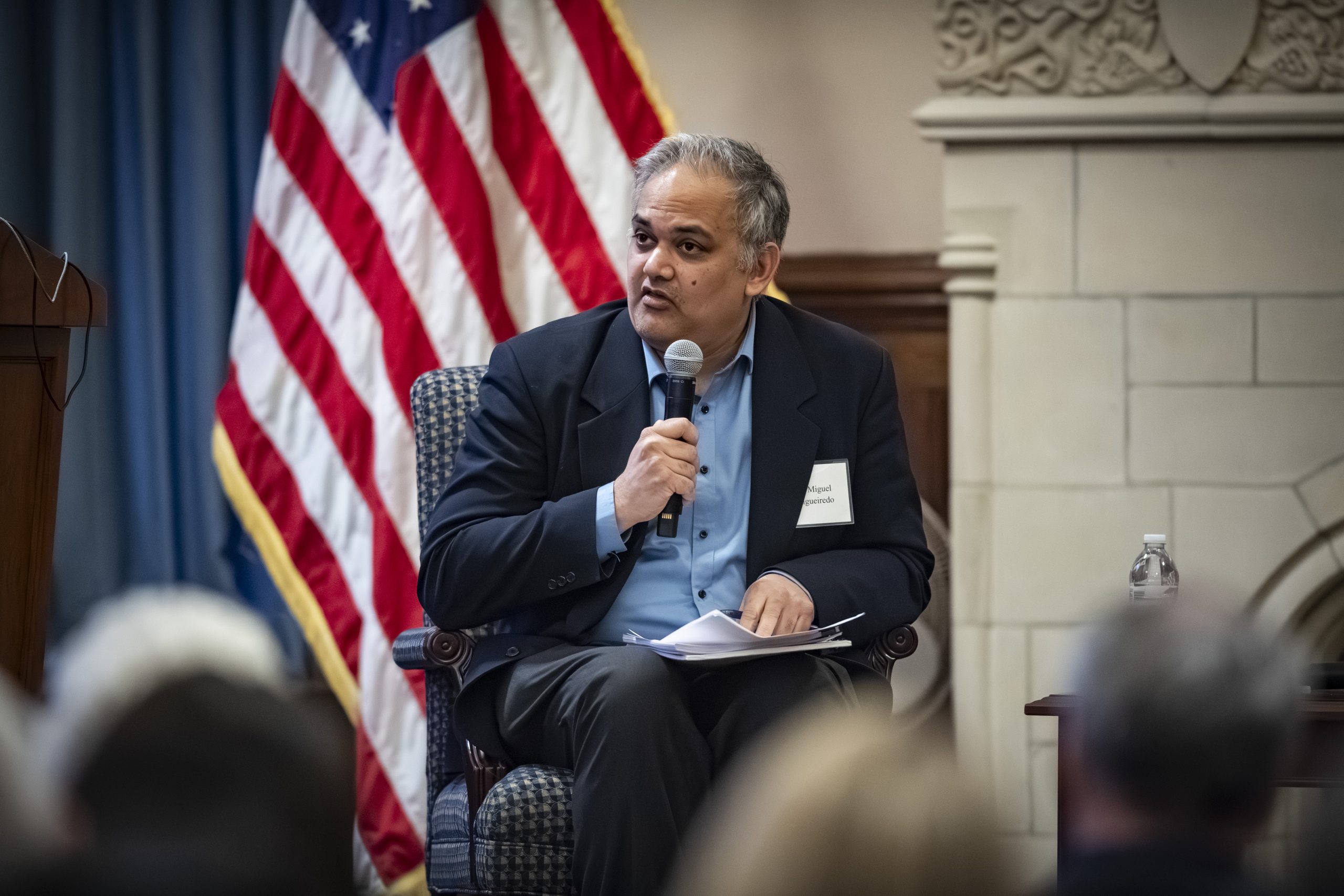 A man sitting in a chair speaking into a microphone